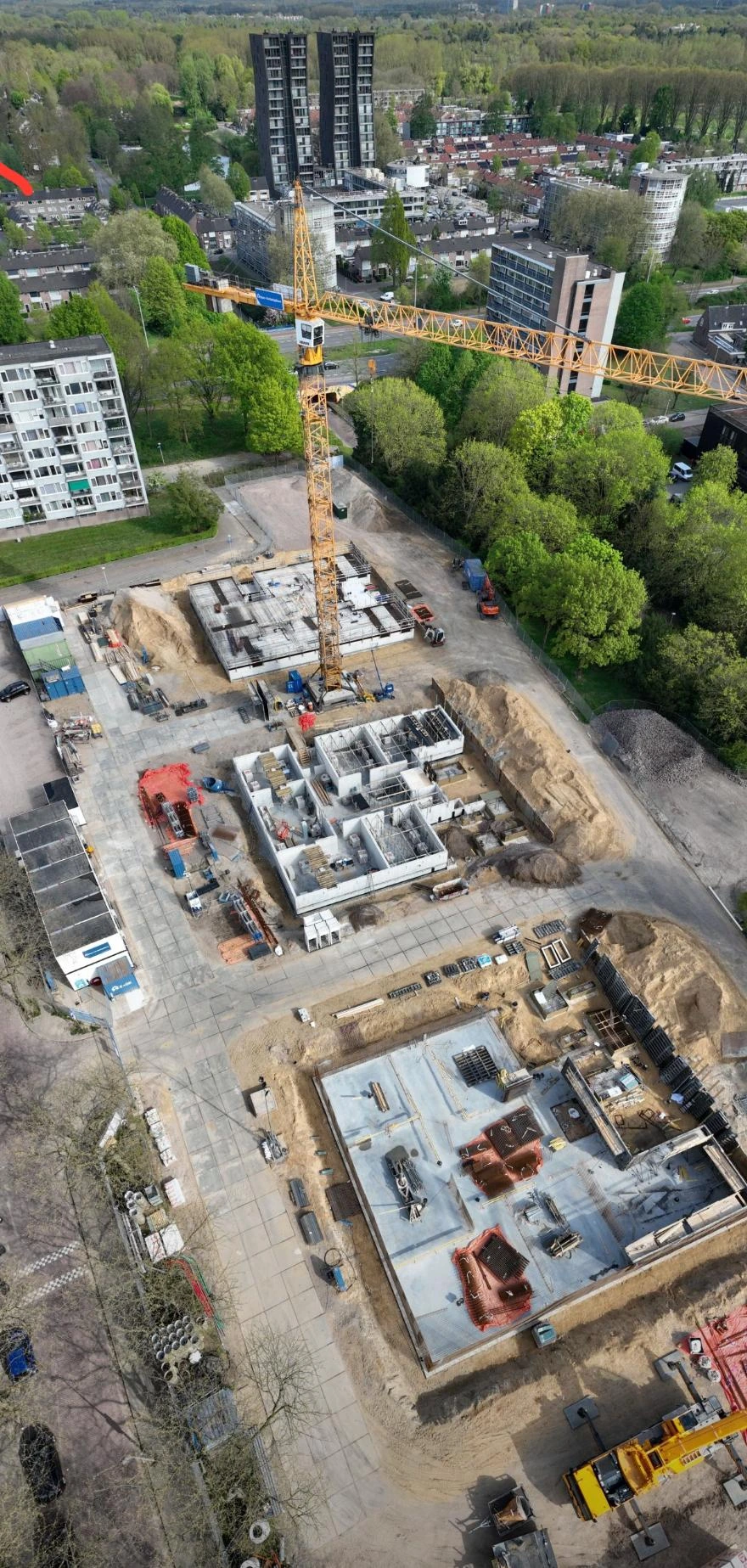 Luchtfoto van een bouwproject met funderingen en casco in uitvoering