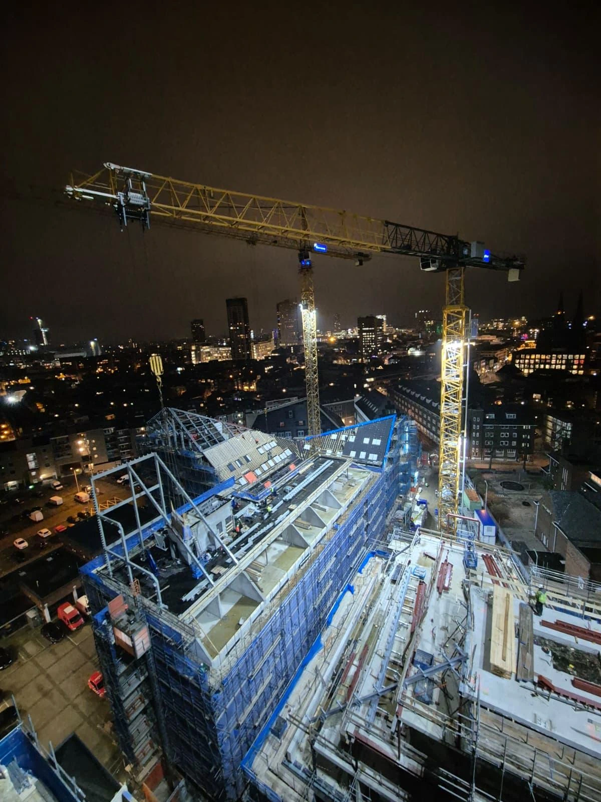 Bouwplaats met verlichte torenkranen boven de stad bij nacht