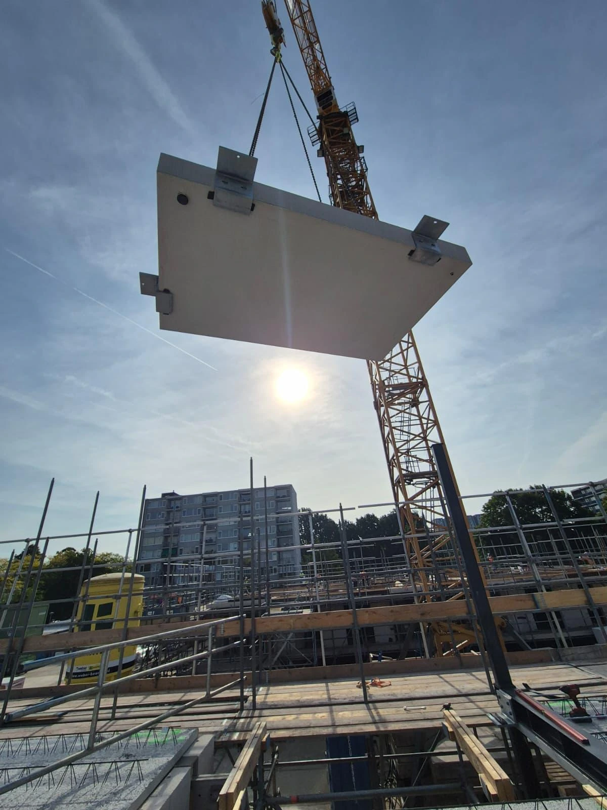 Prefab betonelement aan de kraan boven de bouwplaats
