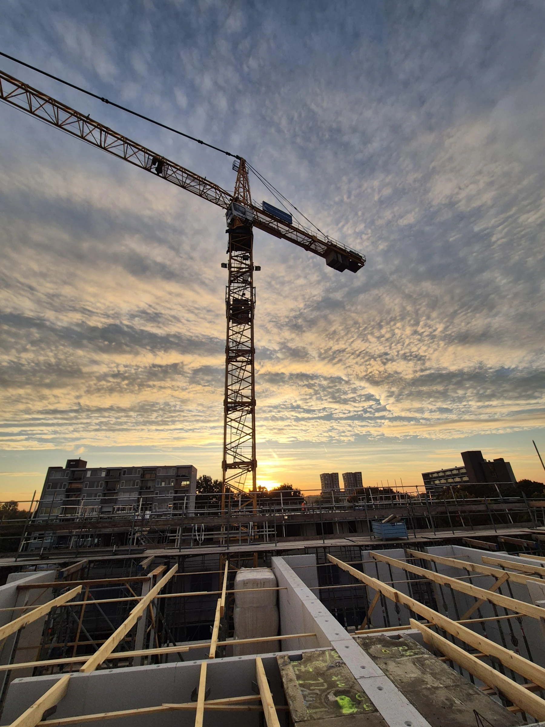 Bouwkraan boven de bekisting van een betonvloer bij zonsondergang